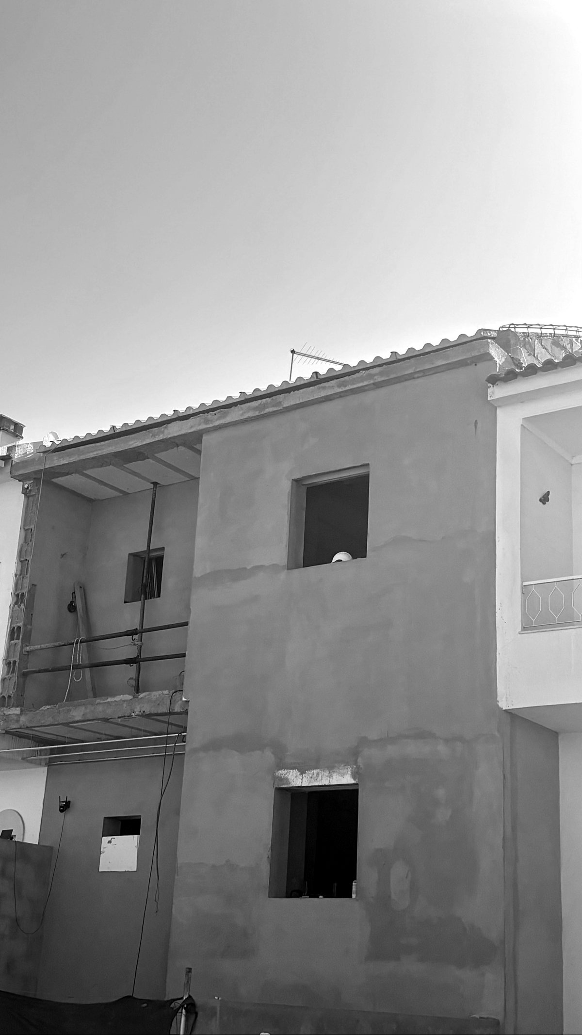 Fachada da moradia em fase de reboco, com vãos abertos e andaime, Vale da Amoreira