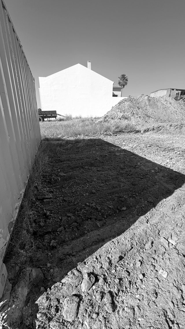 Terreno em terraplenagem junto ao contentor de estaleiro, com maquinaria ao fundo, Montijo — fotografia 1 de 1